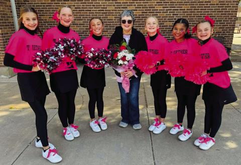 Wellington Junior High School Firecracker cheerleaders and sponsor Heather Proffitt spotlight one of their own, breast cancer survivor Linda Porter, during the pink-out pep rally Thursday, Oct. 17. Porter accepted a bouquet of fresh roses and daisies as a token of their love and support. From left: Libby Chandler, Kaesyn Kane, Claire Kane, Porter, Hartley Kane, Demi Massey and Halle Hedrick. Photo Courtesy of Wellington Junior High School