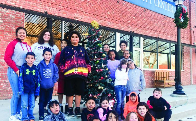 Several Wellington Opportunity Center, Inc. (WOCI) students and staff gather around the Christmas tree on the westside of the Collingsworth County Courthouse Square prior to dismissal of the fall session. Contributions to WOCI can be mailed to P.O. Box 122, Wellington, TX 79095. The Red River Sun/Bev Odom