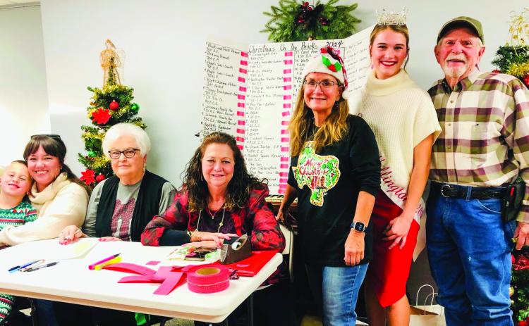 The Collingsworth County Chamber of Commerce Red Ticket Drawing Committee conducts the 2024 drawing at 4:30 p.m. Thursday, Dec. 19 in the Ellis Art Center of the Collingsworth County Museum. From left: Drake and Rachae Barlow, Nancy Harris, Margret Wood, Karen Caldwell, Miss Wellington Maggie Tillman and Billy Wilkerson. The Red River Sun/Bev Odom