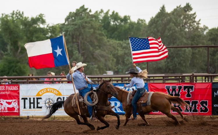 Rodeo fans rise to their feet as the father-daughter duo of Todd and Ellie Thomas carry the colors in the July 1, 2022, performance of the Wellington Fourth of July Rodeo. Witness the 2025 event scheduled for Thursday, July 3-Saturday, July 5 at the Wellington Fairgrounds.