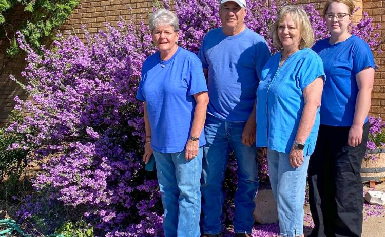 At its best bloom, the SOS from Texas crew admires the vibrant purple blooms of the Texas sage in front of the SOS shop in Samnorwood, headquartered in the former Samnorwood High School. From left: Kathie Lloyd, 15-year employee; owner Gary Oldham; Mona Darrow, 30-year employee; and Allison Bentley, five-year employee.