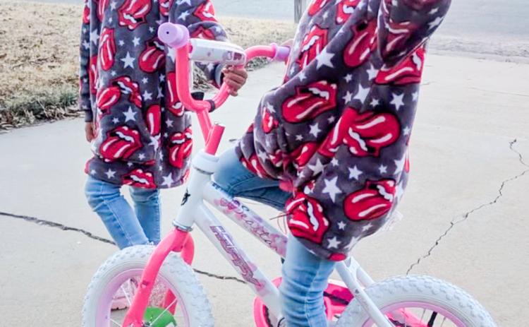 Amiyah Stanley, alongside her twin sister, Armani, takes her new bike for a test ride. The daughters of Cody Stanley, Amiyah won the girl’s bicycle drawing during the Saturday evening, Dec. 6 Collingsworth County Chamber of Commerce Christmas on the Bricks event.