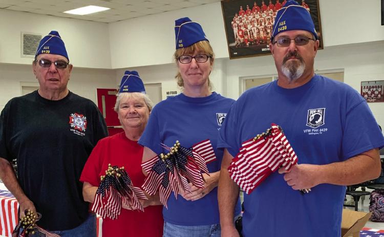 Upon entry to the Veterans Day event, Bruce and Diane Vanderplaats and Dawn and Shane Popwell, members of Glynn Moore VFW Post 6439 Auxiliary, present each visitor a U.S. flag. Courtesy Photo