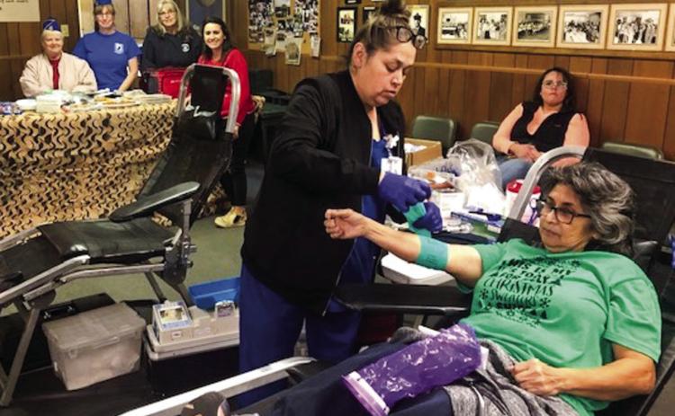 Irma Thomas completes her blood donation during the 12 Days of Christmas Coffee Memorial Blood Center drive at VFW Post 6439. Members of the Post Auxiliary, in the background, include Diane Vanderplaats, Dawn Popwell and Doris Wilbur, plus Ashly Cantu and Lucy Owens (seated). The Red River Sun/Bev Odom