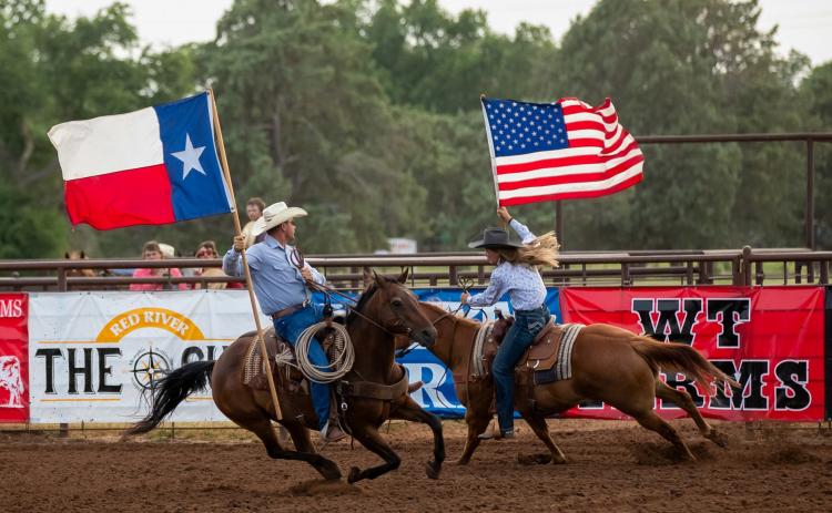 Rodeo fans rise to their feet as the father-daughter duo of Todd and Ellie Thomas carry the colors in the July 1, 2022, performance of the Wellington Fourth of July Rodeo. Witness the 2025 event scheduled for Thursday, July 3-Saturday, July 5 at the Wellington Fairgrounds. HZW Media