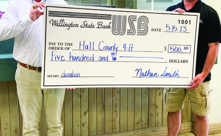 Hall County 4-H, represented by Christian Brooks, left, accepts a $500 donation from Wellington State Bank Senior Vice President Nathan Smith Monday, May 15. Photo Courtesy of Hall County 4-H