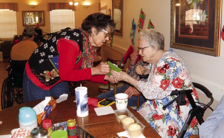 Rothwell Circle of United Women in Faith of Childress Methodist Church member Lila Hoobler presents Cottage Village Assisted Living and Retirement Center resident Billie Simmons a stocking at the Christmas party Tuesday, Dec. 14. Grace Holman Photos