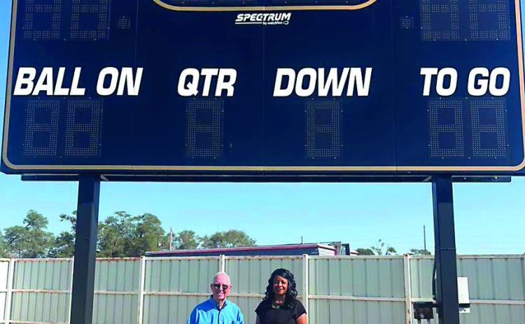 First Bank &amp; Trust President Steve Hall and Assistant Vice President Charolette Maddox stand under the new Cyclone Football scoreboard. The bank purchased the scoreboard that will elevate the game-day experience for Cyclone players, students, and fans alike. The new scoreboard reflects a shared dedication to celebrating local youth MISD PHOTO