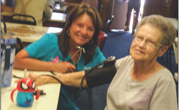 Angels Care Home Health Account Executive Melissa Conner, of Vernon, takes a blood pressure reading for Jannas Watson at the Childress Busy Beavers hamburger fundraiser Friday, June 14 at the Childress Senior Citizens Center. Photos by Grace Holman