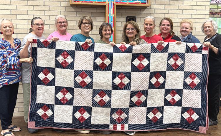 Wellington First Methodist Women, including Charlotte Stephens, Beckie Adams, Lori O’Rear, Donnie Carter, Janie Thomas, Karen Caldwell, Lisa Manuel, Amy Henard, Leslie Schnaufer Bell, and Sandy Sain, display the 2026 patriotic fundraiser quilt to be given away at the upcoming Saturday, Nov. 7 bazaar. INTREPID PHOTO / BEV ODOM
