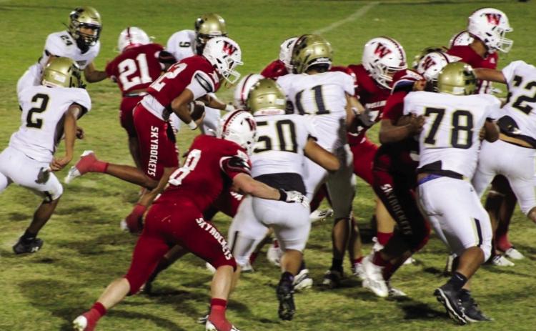 Wellington Skyrockets, including Caleb Strickland (8) and Travon Lewis (21) block out the Memphis Cyclone defensive line while ballcarrier Braylon Tarver (12) puts up yardage. The Red River Sun/Shauna Salinas