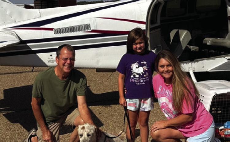 Volunteer pilot Bill Mastin, of Weatherford, delivers Farris from a shelter in East Texas to Wellington Sunday morning, Aug. 4. Wellington Rescue Shelter founder Andi Duke, right, and daughter Sherree, accept delivery of the heeler mix. Courtesy Photo