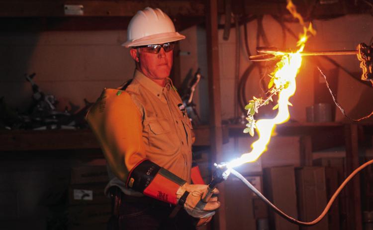 Journeyman Lineman Jeff Frosts demonstrates how tree branches can become a danger when swaying too close to electrical lines during an arcing demonstration presented to area fourth graders Tuesday, Oct. 4. The Red River Sun/Elizabeth Tanner