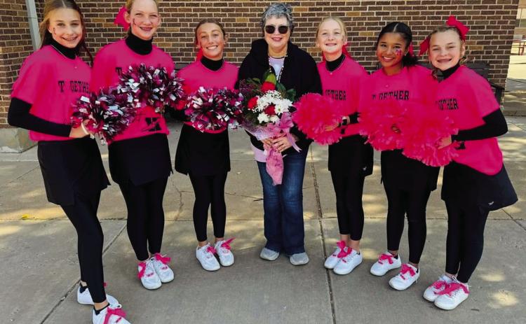 Wellington Junior High School Firecracker cheerleaders and sponsor Heather Proffitt spotlight one of their own, breast cancer survivor Linda Porter, during the pink-out pep rally Thursday, Oct. 17. Porter accepted a bouquet of fresh roses and daisies as a token of their love and support. From left: Libby Chandler, Kaesyn Kane, Claire Kane, Porter, Hartley Kane, Demi Massey and Halle Hedrick. Photo Courtesy of Wellington Junior High School