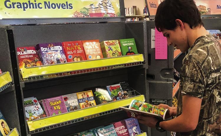 An avid reader, Wellington High School junior Marcus Lopez grabs a book from the display case during Collingsworth Public Library’s recent Literati Book Fair. Not able to put the book down, Lopez ended up purchasing his find. The Red River Sun/Bev Odom
