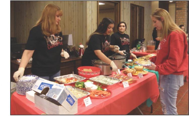 Peoples Federal Credit Union hosts a Christmas Open House Tuesday, Dec. 13, inviting customers, many of which arrived in yuletide attire, for refreshments. Peoples Federal Credit Union employee Kenja Parkey, of Amarillo, serves customer Shasta Underwood. Photos by Grace Holman