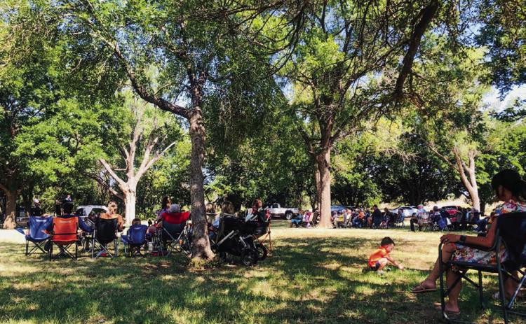 Venturing a short distance from his family, three-yearold Bexton Brooks, son of Travis and Kelsey Brooks, of Childress, makes the most of his Sunday morning worship time at Pioneer Park, adding to his grasshopper collection. The Red River Sun/Bev Odom