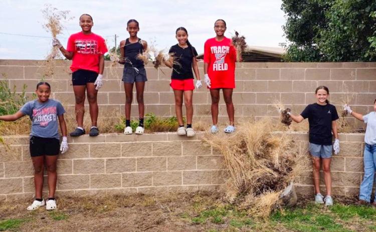 Coached by Prentice Coffee and Yael Garcia, the 2032 Lady Rockets, including, from left, Brilynn Coffee, Aliyah Coffee, Jaedah Casas, Aryen Garcia, Aubrey Coffee, Berkeley Ward and Penelope Hernandez, clean the flowerbeds of Wellington Fairgrounds prior to the Fourth of July events this weekend. Teammates out of town at the time were CJ Henard, Kenlea Martin and Mariah Medina Courtesy Photo