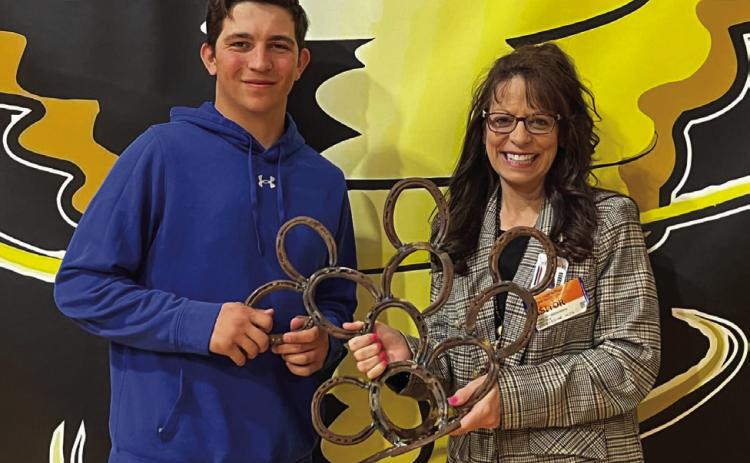 Memphis High School senior Jase Middleton presents a cactus sculpture, which he welded out of horseshoes at the Memphis Independent School District (ISD) Career Training Center, to Region 16 Education Service Center Coordinator of Accountability, Assessment and School Improvement Christine Scroggs. Photo Courtesy of Memphis ISD