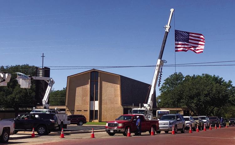 Members of Greenbelt Electric Cooperative, Inc. line 9th St. in Wellington Friday, Sept. 23 for the annual drive-thru meeting as Old Glory stretches out amongst powerlines. The Red River Sun/Bev Odom